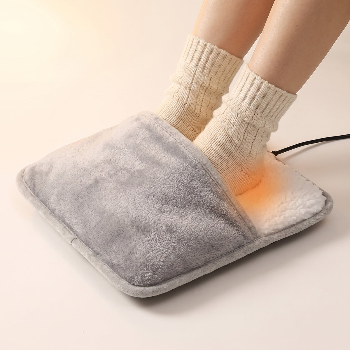 Chancelière chauffante en flanelle grise et peluche blanche, deux pieds en chaussettes glissés à l'intérieur