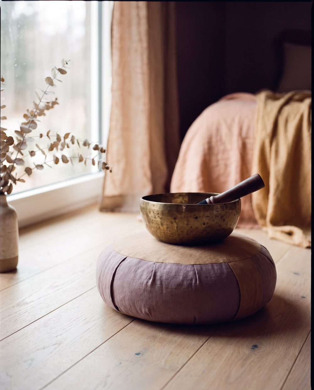 Bol chantant en laiton et son maillet posés sur un coussin de méditation